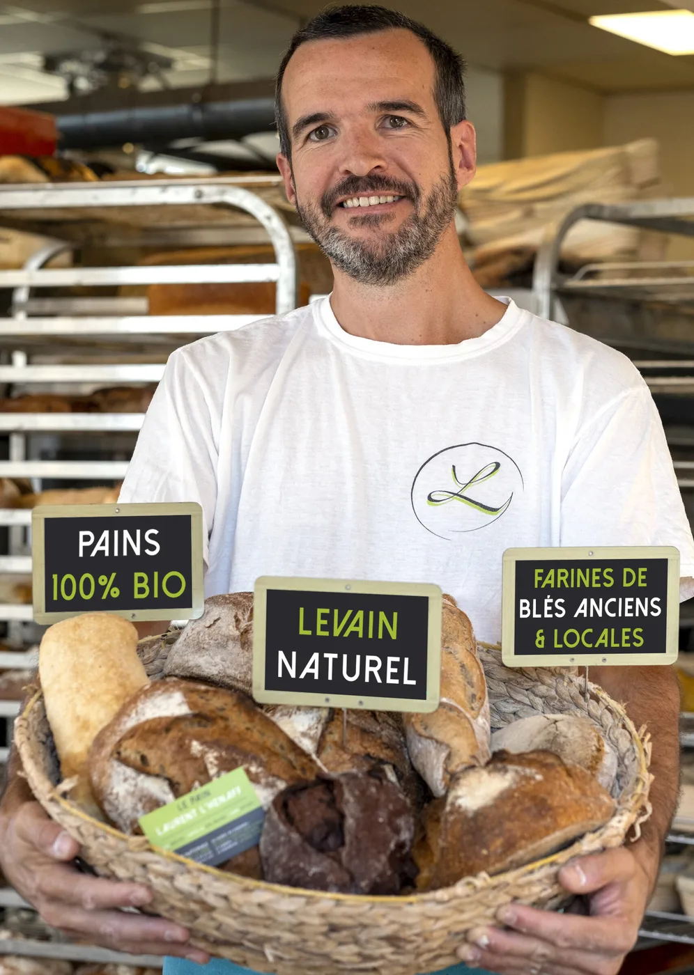 Laurent L'Hénaff dans son fournil, un panier de pains bio au levain dans les mains